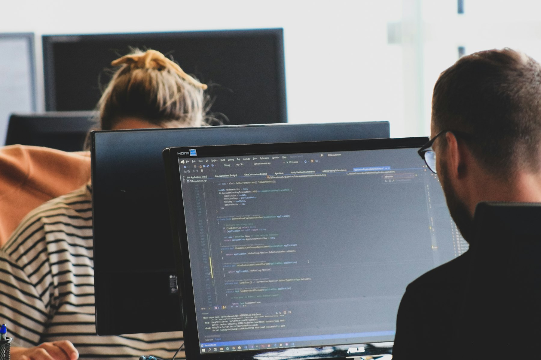 Engineers at monitors, working through code